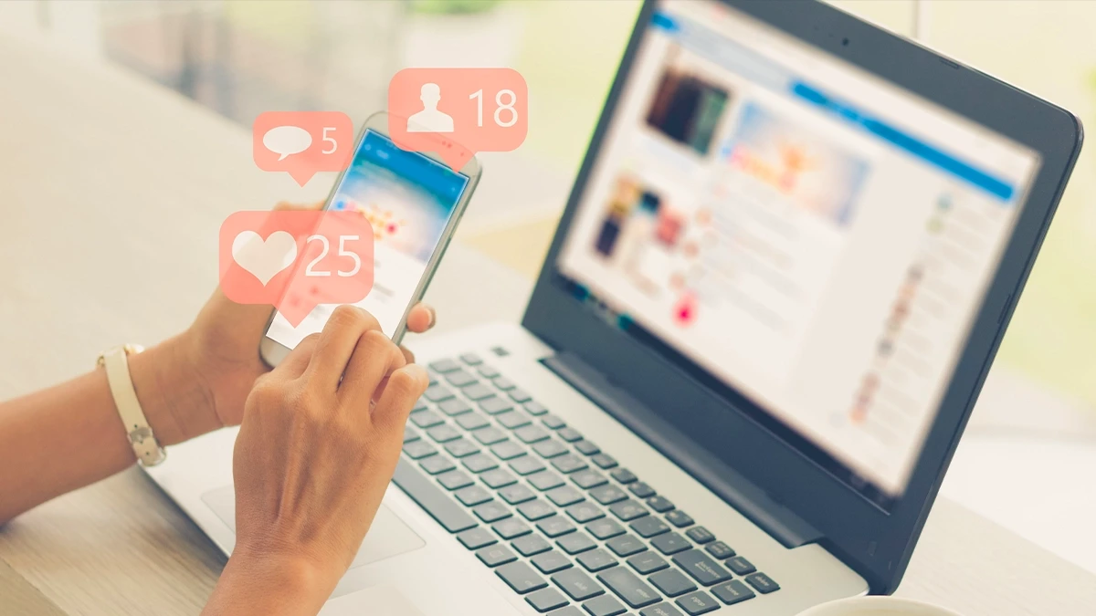 Phone and laptop showing likes, comments and follower notifications on a business page