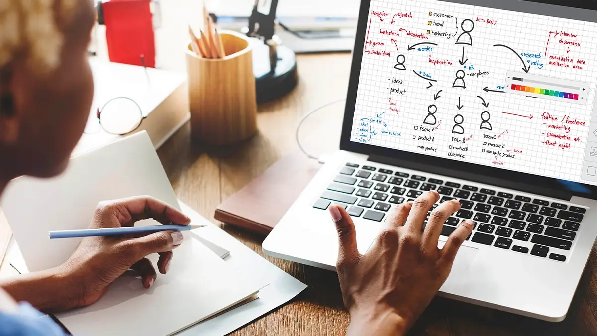 Person mapping out an audience and marketing strategy diagram on a laptop while taking notes