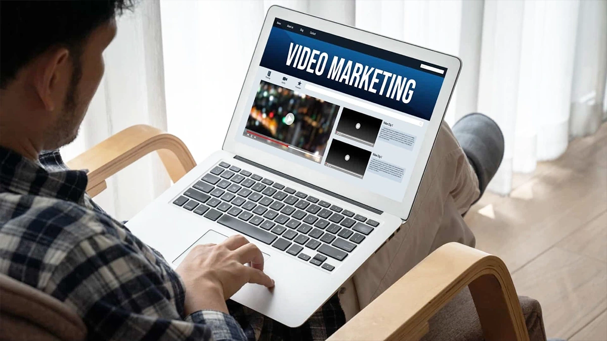 Person browsing a video content library on a laptop showing multiple clips and playback options